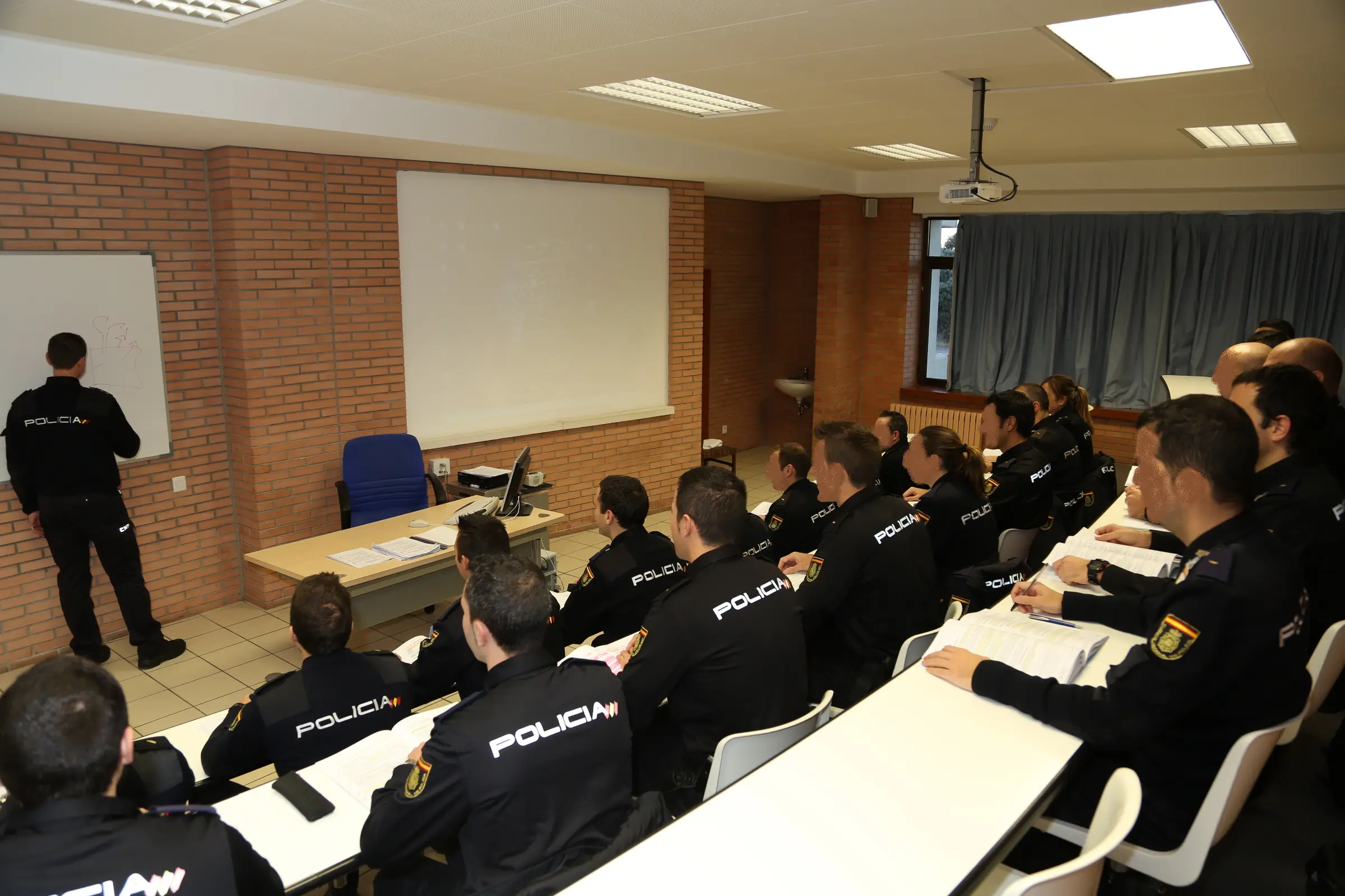 Alumnos de la Escuela Nacional de Policía en clase, con POLICÍA en la espalda